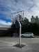 Basketball post and hoop tower on an outdoor court with a car in the background