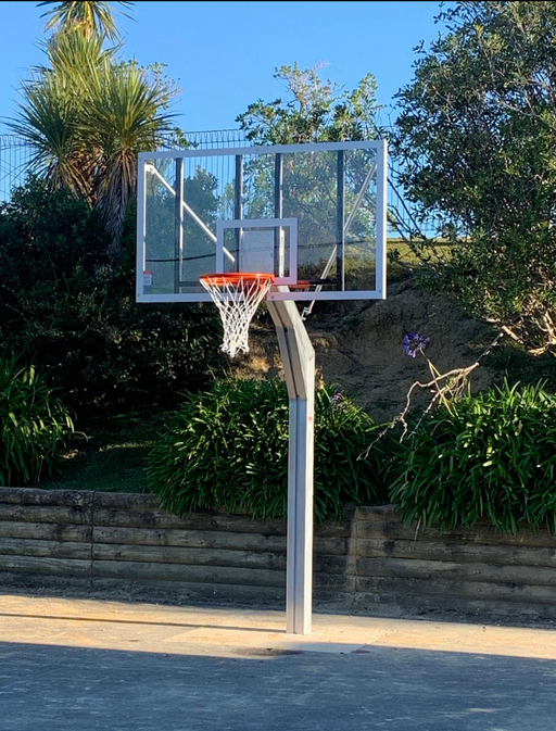 Basketball post and hoop tower on an outdoor court with trees and a clear sky in the background