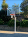 Basketball post and hoop tower on an outdoor court with trees and a clear sky in the background