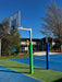 Basketball post, with post pad, on a playground with trees and buildings in the background