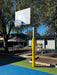 Basketball post, with post pad, on a playground with trees and buildings in the background